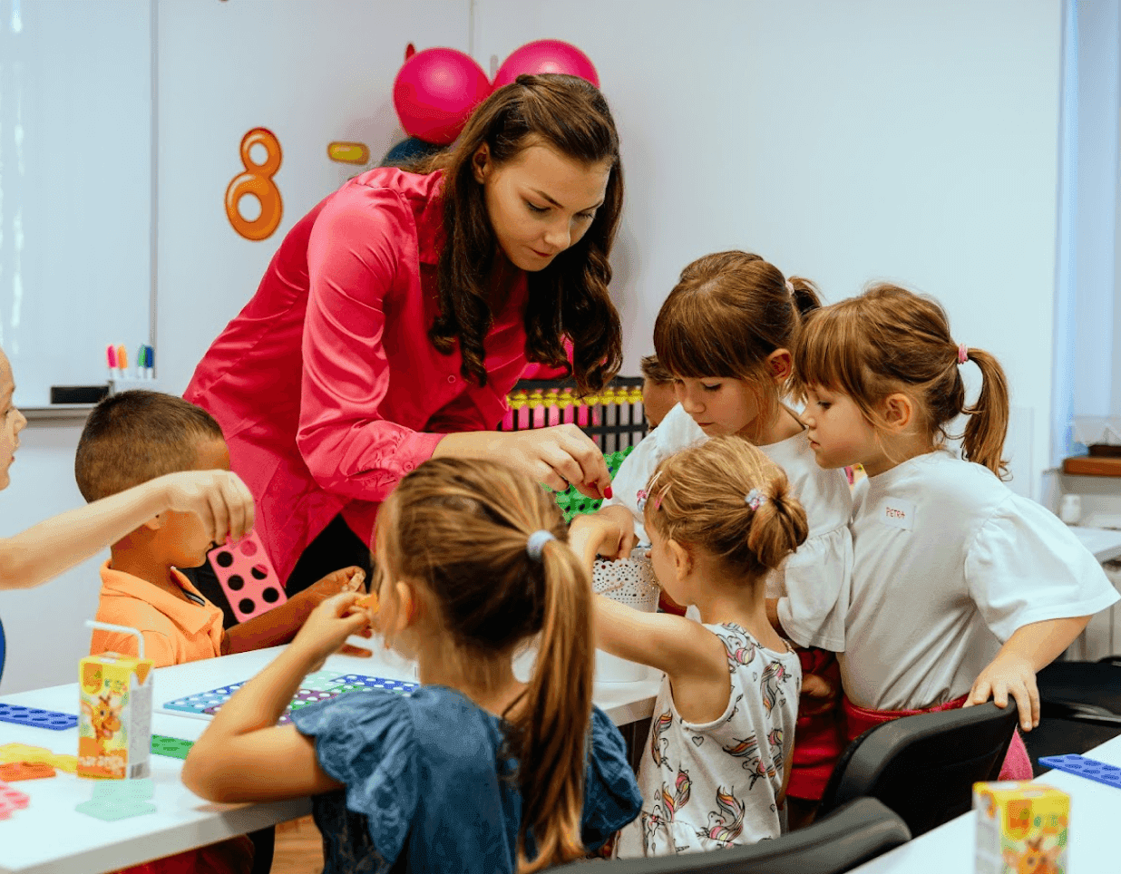 Učiteljica za stolom pokazuje skupini djece kako se računa na abakusu