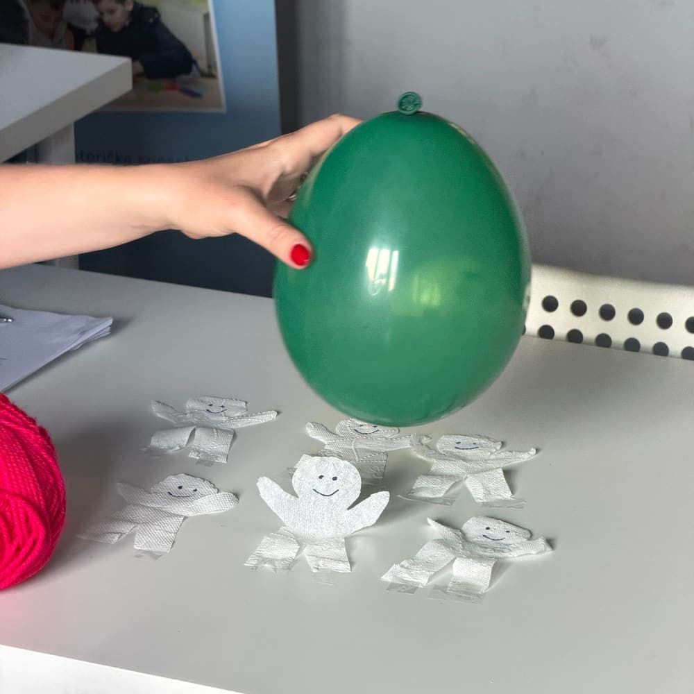 Naelektrizirani balon iznad papirnatih figurica koje se podižu prema njemu